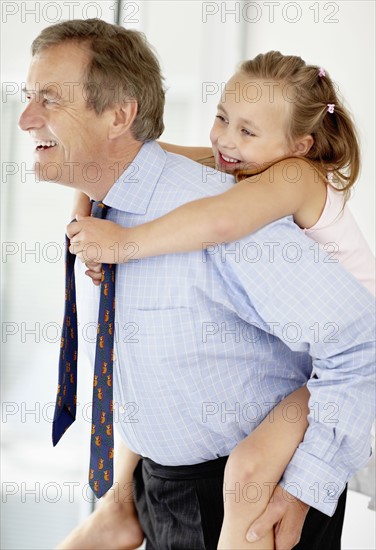 Father carrying girl (10-11) on back. Photo : Momentimages