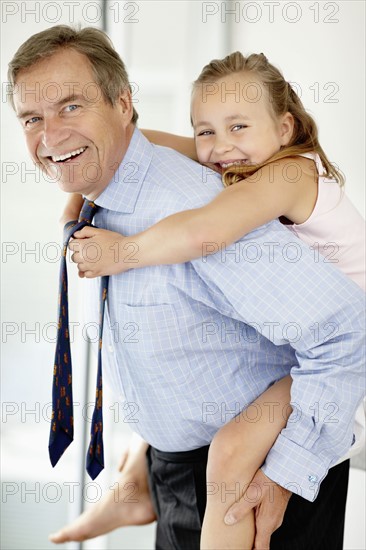 Father carrying girl (10-11) on back. Photo : Momentimages