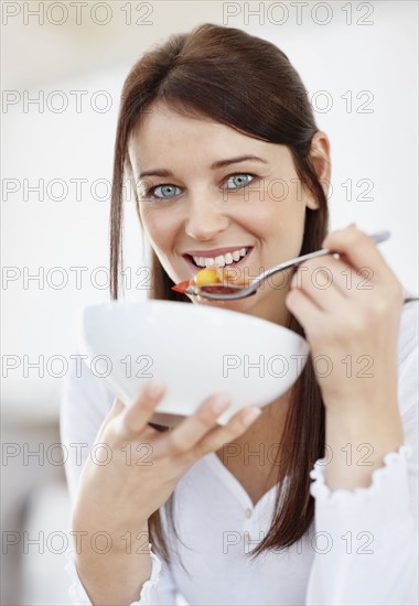 Portrait of mid adult woman eating from bowl. Photo : Momentimages