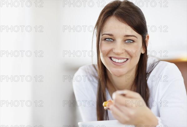 Portrait of mid adult woman eating from bowl. Photo : Momentimages