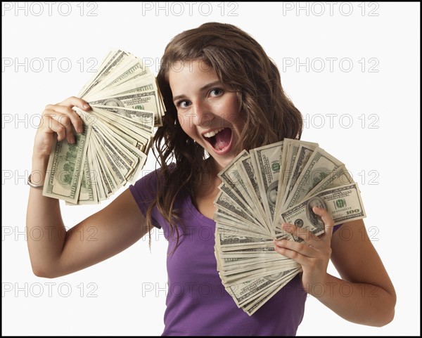 Young woman holding fanned out banknotes. Photo : Mike Kemp