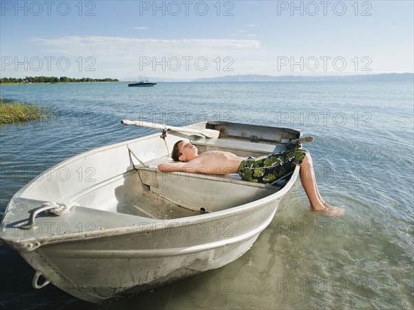 Boy (10-11) resting on boat.
