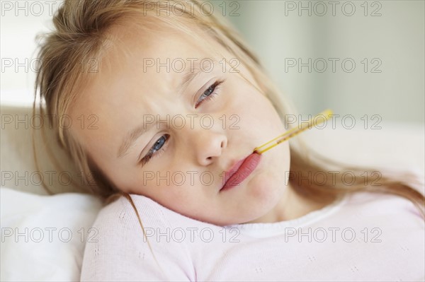 Girl (10-11) checking temperature with thermometer. Photo : Momentimages