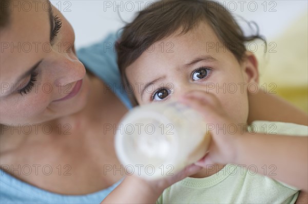 Mother feeding baby daughter (12-18 months) .