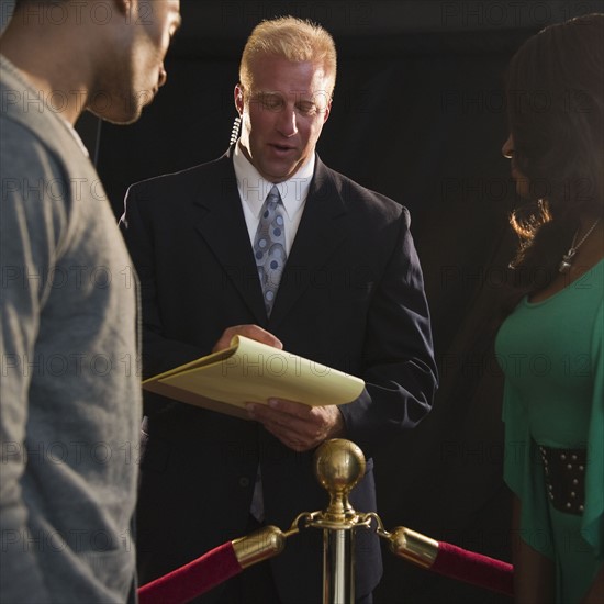 Bouncer checking invitation at red carpet event. Photo : Jamie Grill