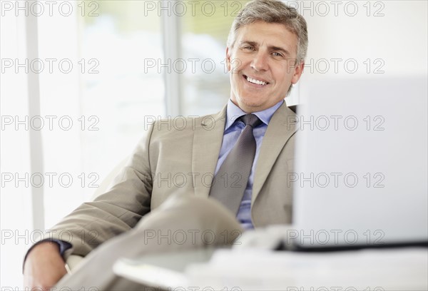 Portrait of cheerful businessman with laptop. Photo : Momentimages