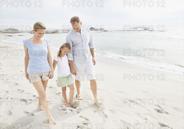 Girl (10-11) playing on beach with parents. Photo : Momentimages