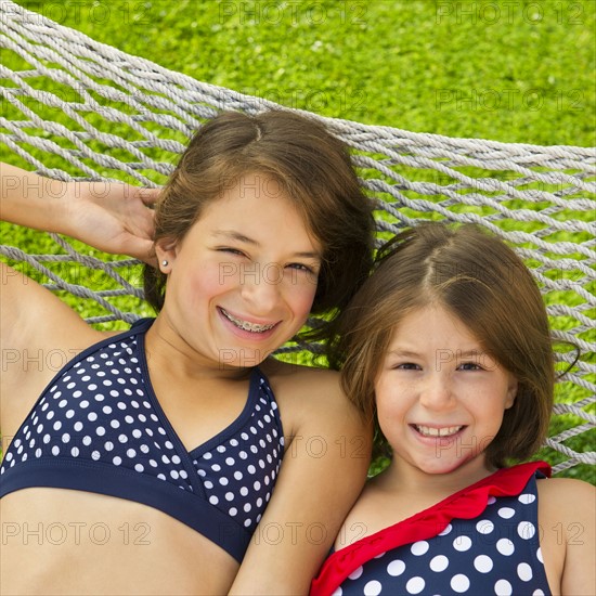 Portrait of sisters (8-9, 12-13) lying in hammock. Photo : Daniel Grill