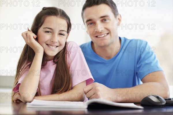 Father helping daughter (10-11) do homework. Photo : Momentimages