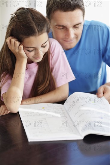 Father helping daughter (10-11) do homework. Photo : Momentimages