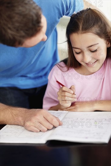 Father helping daughter (10-11) do homework. Photo : Momentimages