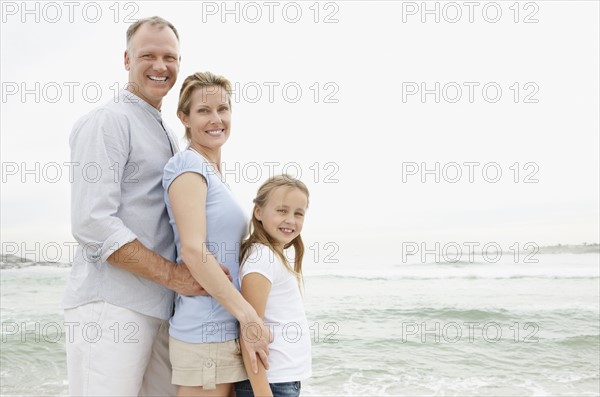 Smiling family standing at beach and looking at camera. Photo : Momentimages