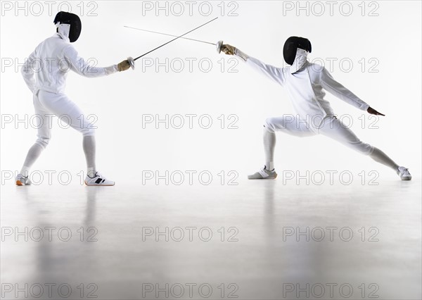 Studio shot of fencers in attacking lunge.