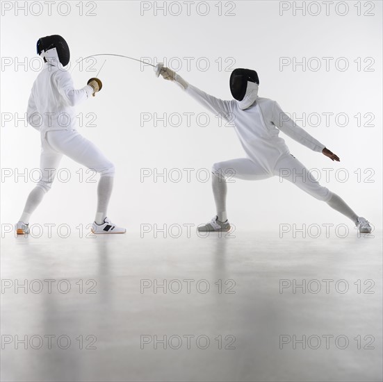 Studio shot of fencers in attacking lunge.