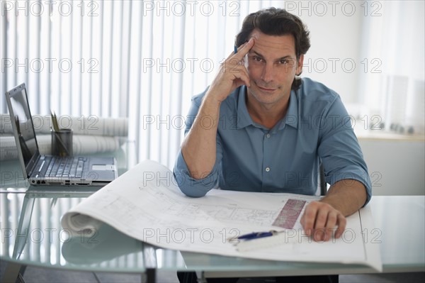 Architect with blueprints in office.