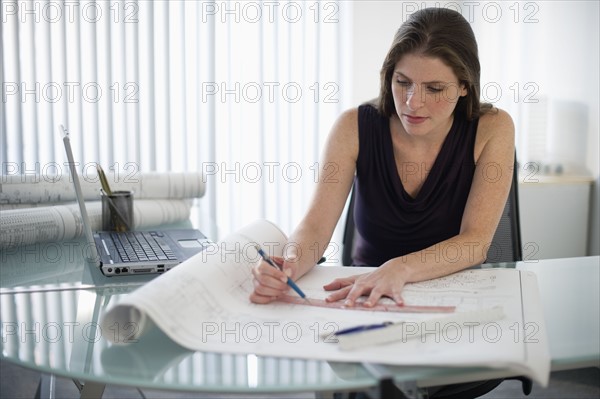 Female architect with blueprints in office.