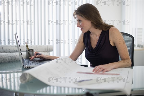 Female architect with blueprints in office.