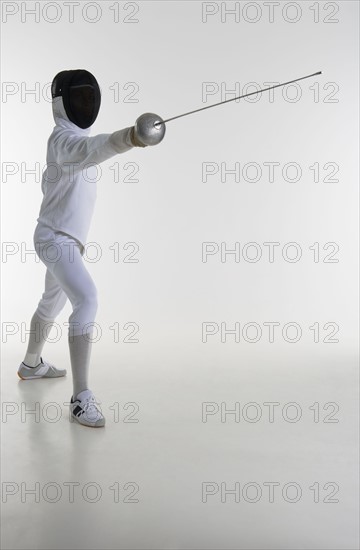 Studio portrait of fencer holding fencing foil.