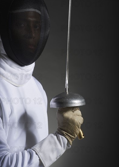 Studio portrait of fencer holding fencing foil.