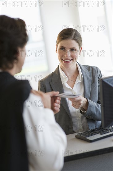 Woman in office giving ticket to customer.