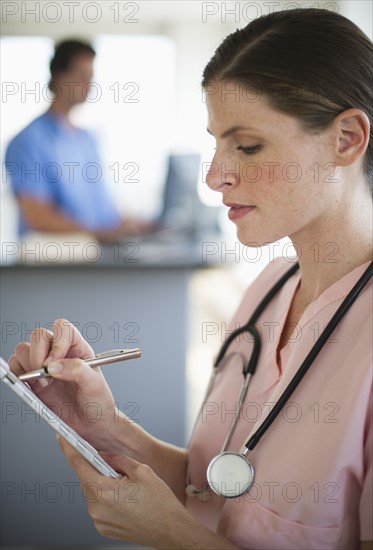 Female doctor writing documentation in hospital.