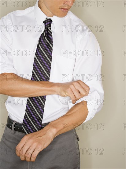 Businessman rolling up sleeves. Photo : Jamie Grill