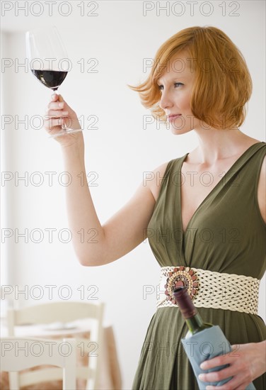 Young woman looking at glass of wine. Photo : Jamie Grill