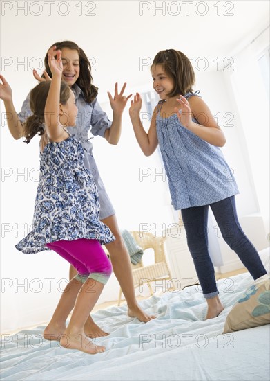 Sisters (2-3, 8-9, 12-13) jumping on bed. Photo : Daniel Grill