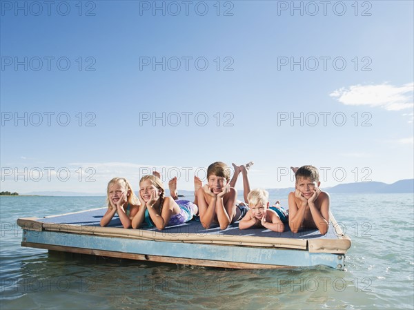Kids (2-3,6-7,8-9,10-11,12-13) playing on raft on lake.
