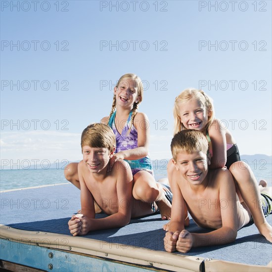 Kids (6-7,8-9,10-11,12-13) playing on raft on lake.