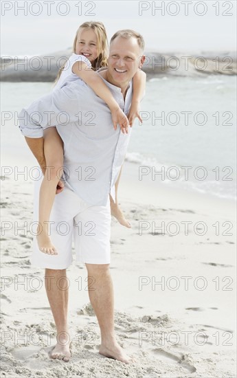 Girl (10-11) playing on beach with father. Photo : Momentimages