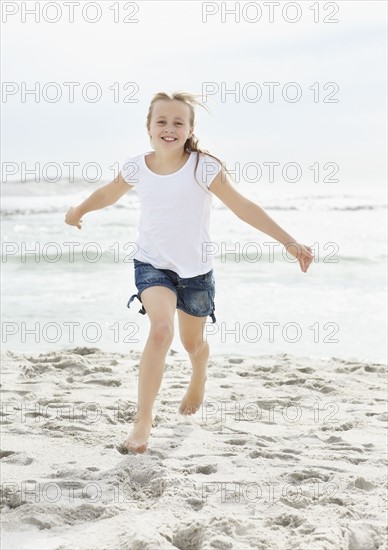 Portrait of girl (10-11) running on beach. Photo : Momentimages