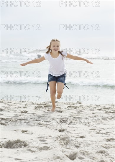 Portrait of girl (10-11) running on beach. Photo : Momentimages