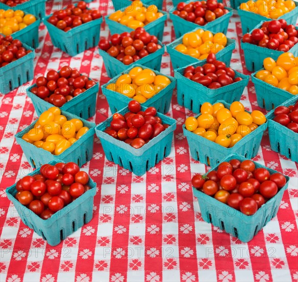 Boxes with cherry tomatoes on table.