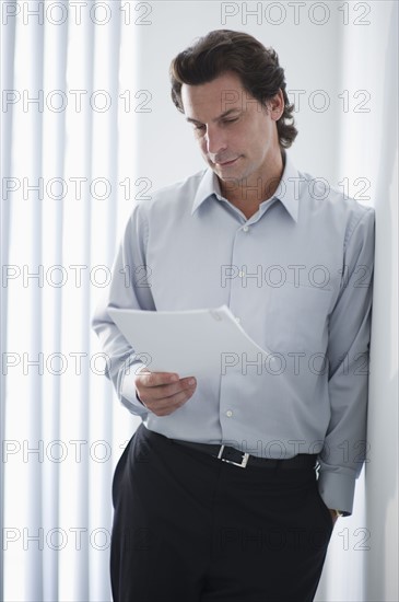 Man in office reading document.