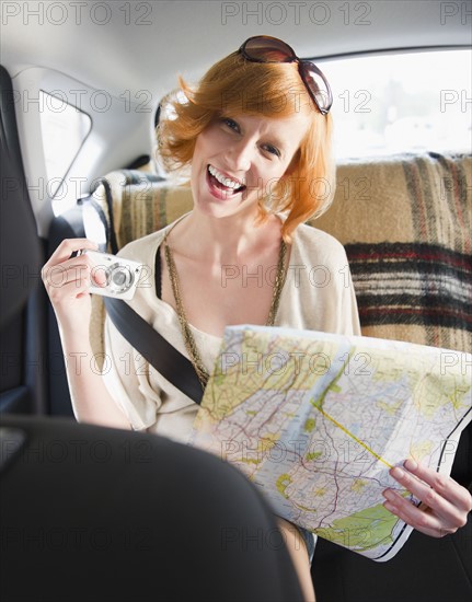 Portrait of young woman holding map in car. Photo : Jamie Grill