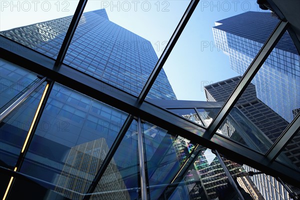 USA, New York State, New York City, Tall skyscrapers seen through glass ceiling of modern office building. Photo : fotog