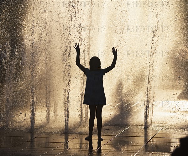 Silhouette of girl playing in fountain. Photo : fotog