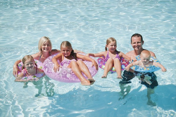 Family with four kids (12-18months, 4-5,6-7,8-9) on swimming pool.