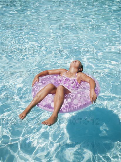 Girl (8-9) floating on rubber ring.