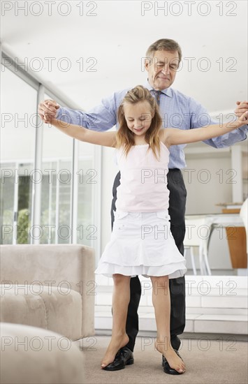 Grandfather dancing with granddaughter (10-11). Photo : Momentimages