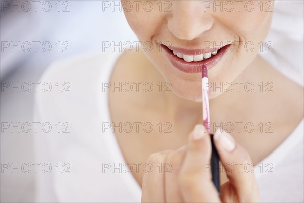 Close-up of woman applying lipstick. Photo : Momentimages