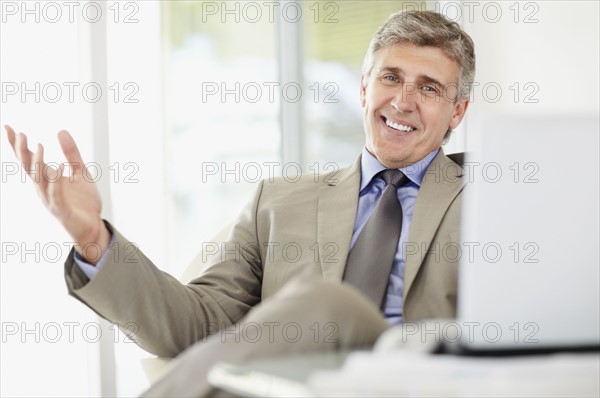 Portrait of cheerful businessman with laptop. Photo : Momentimages