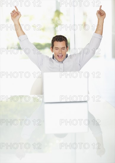 Portrait of enthusiastic man working on laptop. Photo : Momentimages