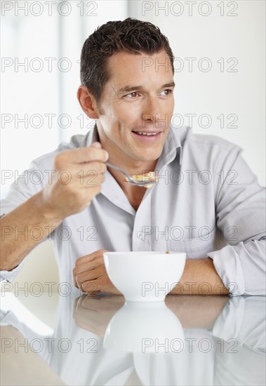 Cheerful mid adult man eating cornflakes. Photo : Momentimages