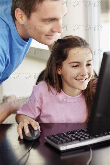 Father with daughter (10-11) playing with computer. Photo : Momentimages