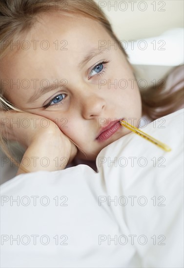 Girl (10-11) checking temperature with thermometer. Photo : Momentimages