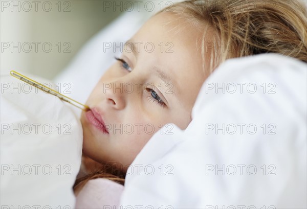 Girl (10-11) checking temperature with thermometer. Photo : Momentimages