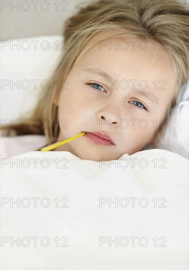 Girl (10-11) checking temperature with thermometer. Photo : Momentimages