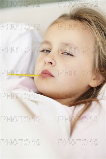 Girl (10-11) checking temperature with thermometer. Photo : Momentimages